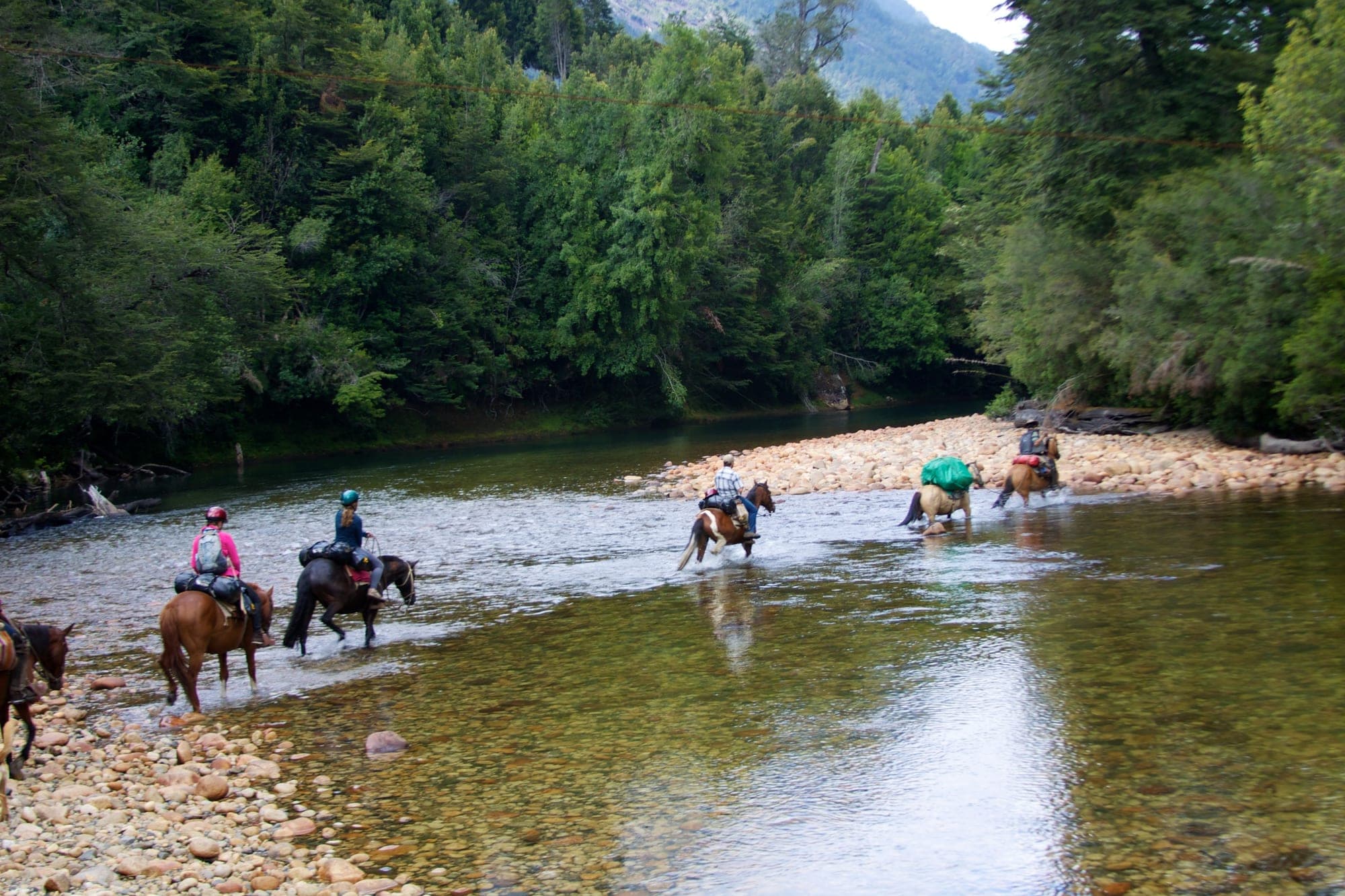 Reiter durchqueren einen Gebirgsfluss